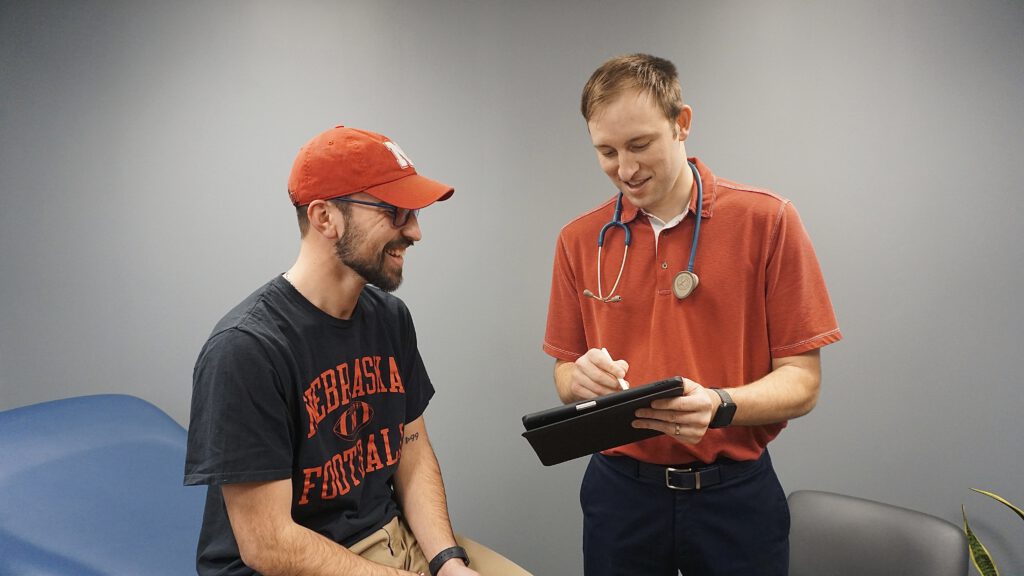 Our provider, Gabriel Dreisbach, going over test results with a patient. Both the patient and Gabriel are looking at a tablet as Gabriel explains how to help the patient.