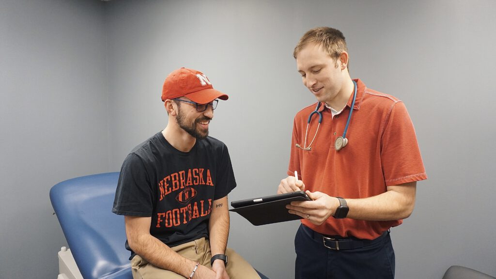 Our provider, Gabriel Dreisbach, going over test results with a patient. Both the patient and Gabriel are looking at a tablet as Gabriel explains how to help the patient. 