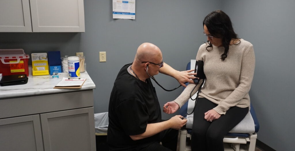 Jason Gillespie, APRN-FNP BC, checking the blood pressure with his patient.