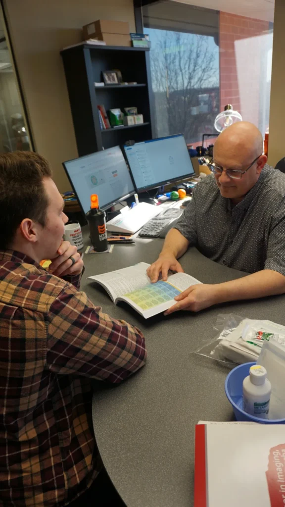 A primary care consultation between Jason and a patient in an office setting, with medical supplies and a computer in the background.